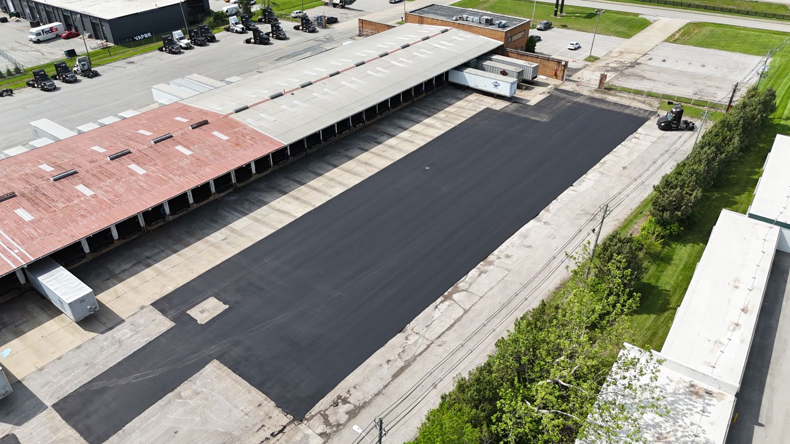 Drone view of a finished asphalt lot beside a long industrial building