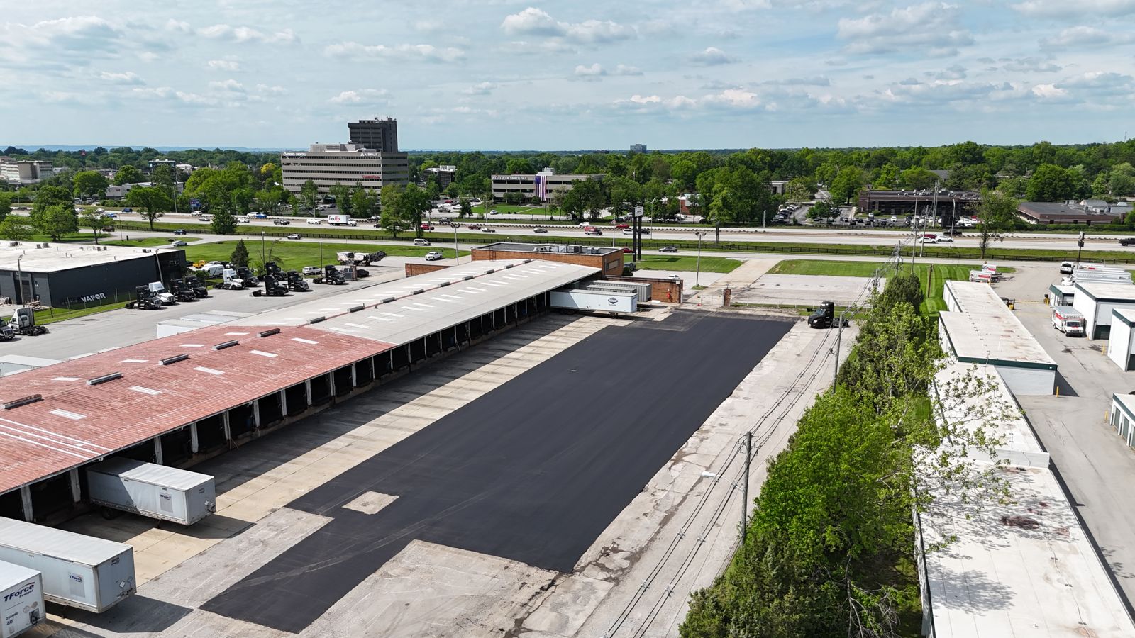 Drone view of a new black lot beside a long warehouse