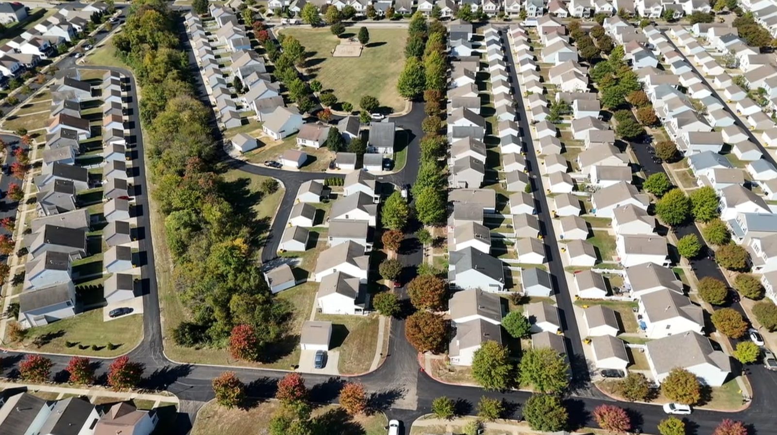 Drone view of a subdivision with fresh black streets around a neighborhood park