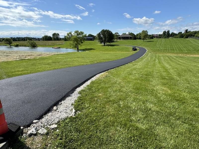 Long new asphalt path through a mowed field