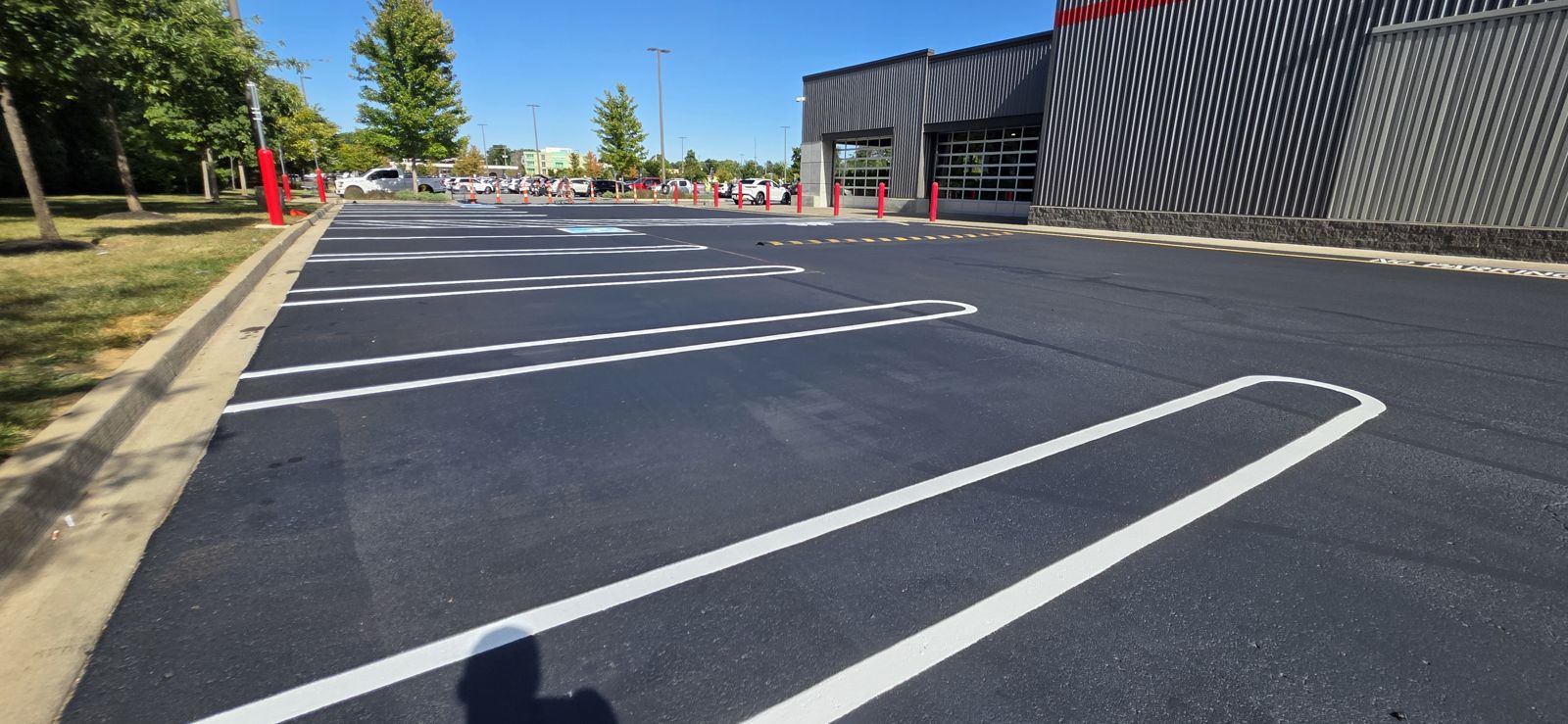 Fresh asphalt lot with new white parking lines beside a metal building